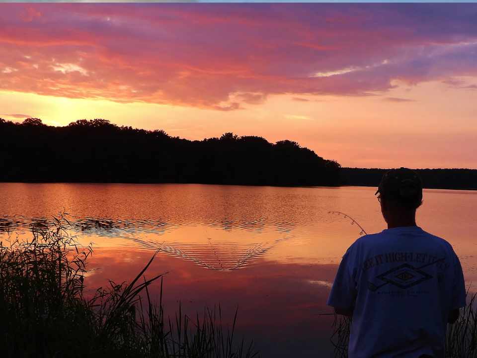 Person fishing at sunset from shoreline